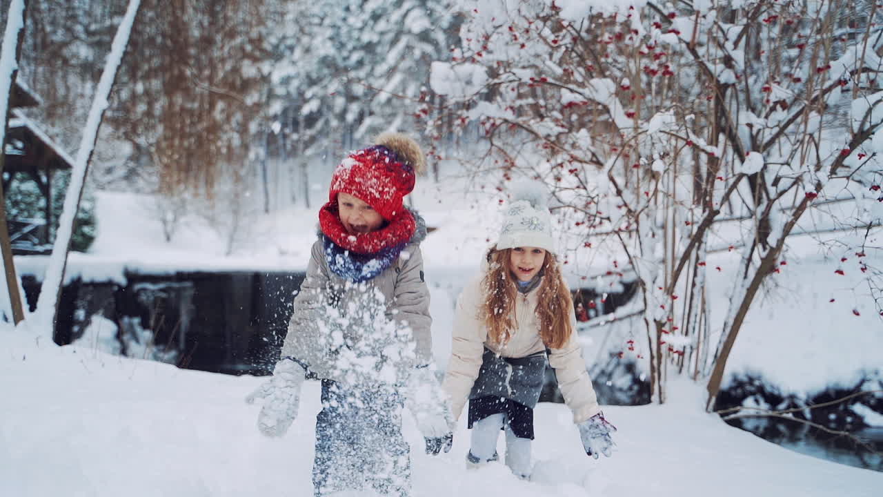 Happy kids playing together with snow. Christmas vacation in sunny winter park. Slow motion.