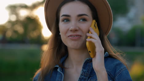 young woman talking on phone in park at sunset