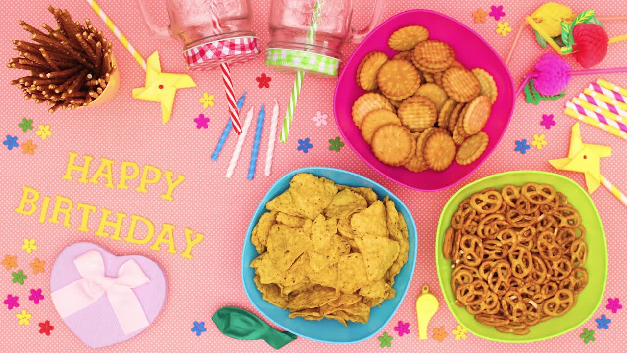 feliz cumpleaños aparecen en la mesa con comida, decoraciones, pajitas, velas, globos para la fiesta - stop motion