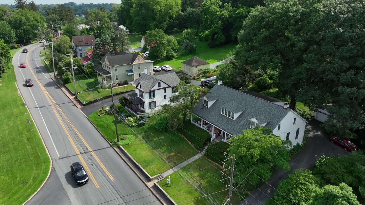 Aerial view of cars on street in suburb of city. Green landscape on hill. Single family house during sunny day in usa. Quiet suburb in summer season. Lush scenic trees and garden on mountains