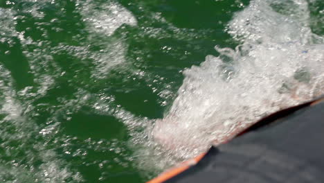 water splashing on the feet of a person cruising on a motorboat during summer - extreme close up
