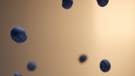 slowmotion shot of blueberries flying up and spinning in front of a warm golden background