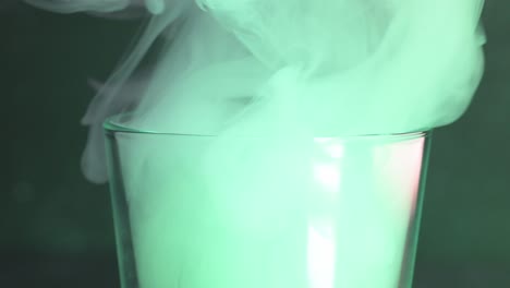 Close-up-of-a-smoke-pouring-into-a-glass-with-green-light