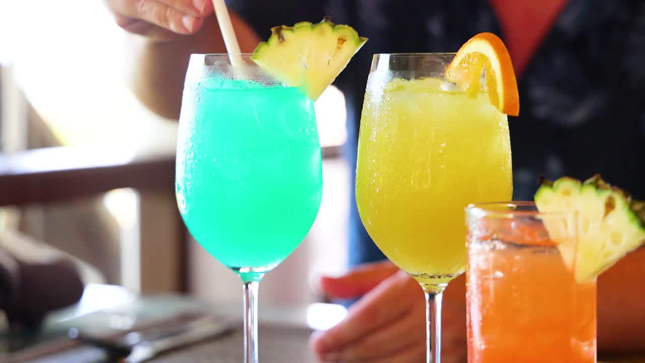 Vibrant cocktails with fruit garnishes prepared in a well-lit environment, showcasing a refreshing and lively atmosphere