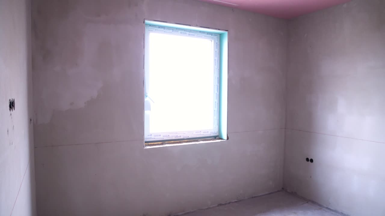 View through unfinished wall opening into empty adjoining rooms during home construction