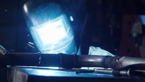 Close-up-of-welder-arc-welding-in-dark-garage-working-on-exhaust