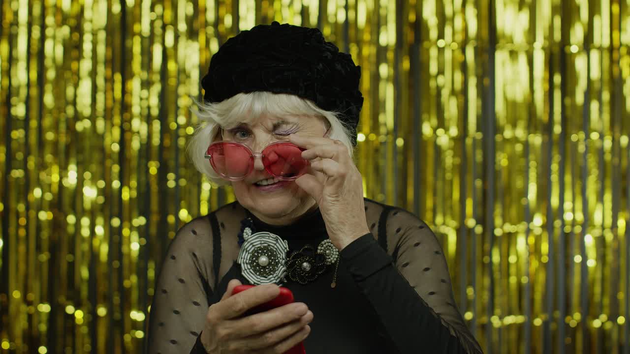 세련된 고령 여성이 소셜 네트워크에서 메시지를 타이핑하고, 앱을 사용하고, 온라인 쇼핑을 하고, 느린 동작을 하고 있습니다.