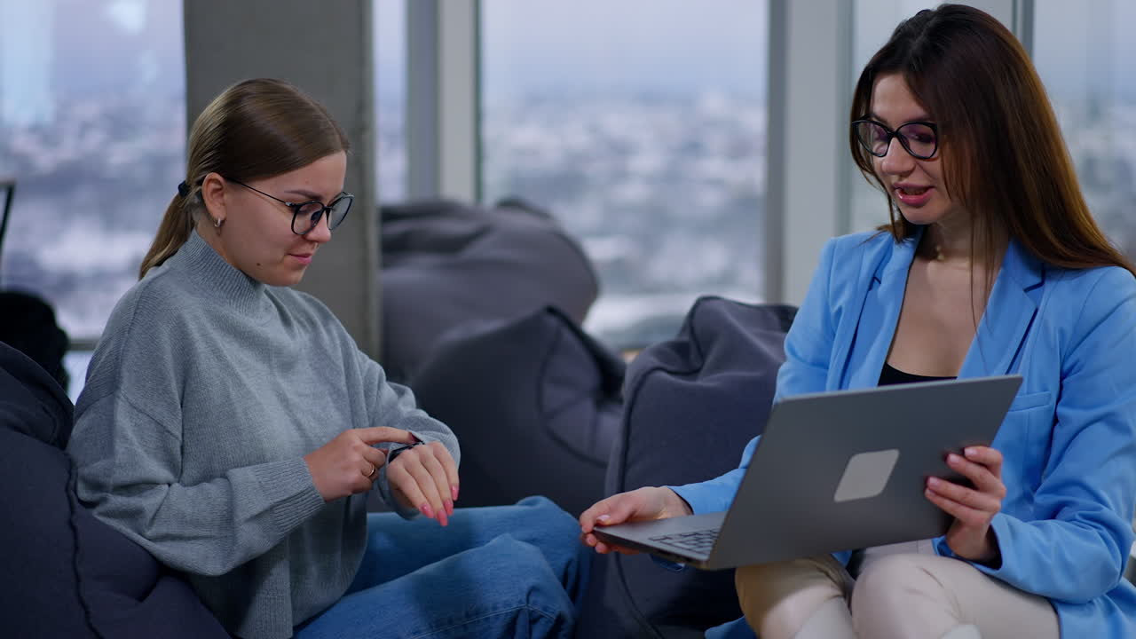 Businesswoman helping a young woman with a laptop
