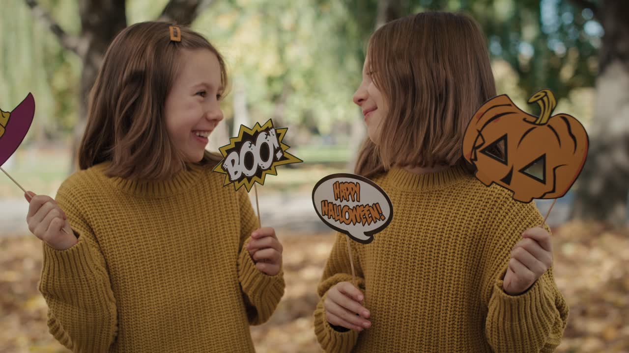 할로윈에 재미있는 마스크를 입은  ⁇ 둥이들이 서 있습니다.