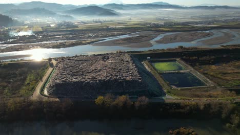 landfill of waste from household dumping site and large tank with contaminated dirty water on river banks