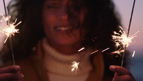 close up sparklers portrait of happy woman celebrating new years eve enjoying independence day celebration having fun on beach at sunset