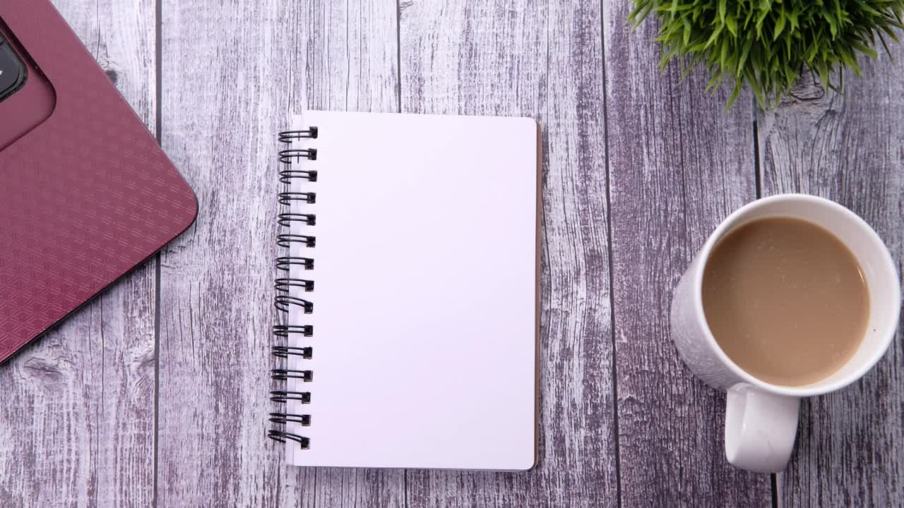 Workspace with notebook, laptop, coffee, and pen