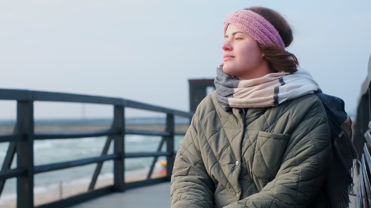Woman contemplating the view from a seaside bridge in winter