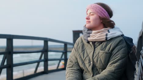 woman contemplating the view from a seaside bridge in winter