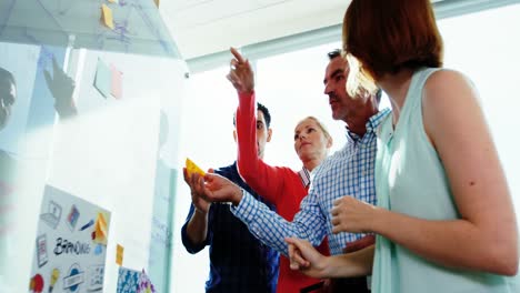 equipo de ejecutivos de negocios discutiendo sobre un tablero de vidrio