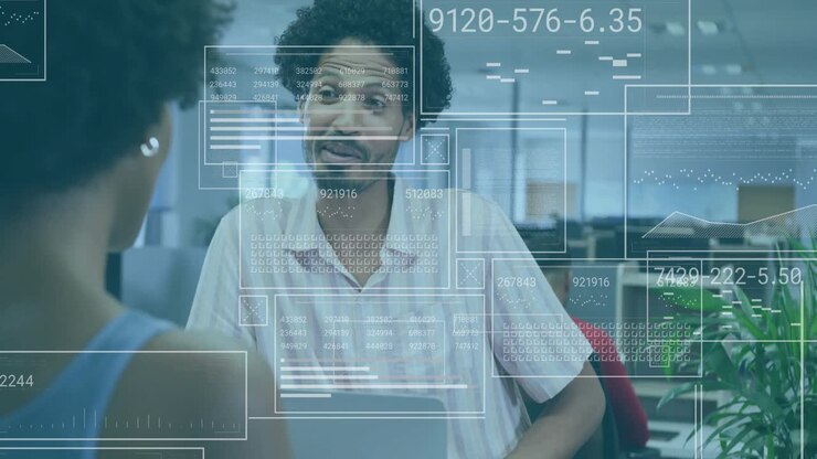 Woman addressing coworker at desk, conversation initiating digital overlays showing finance charts