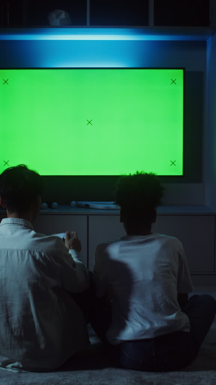 Due bambini che giocano ai videogiochi su uno schermo TV verde