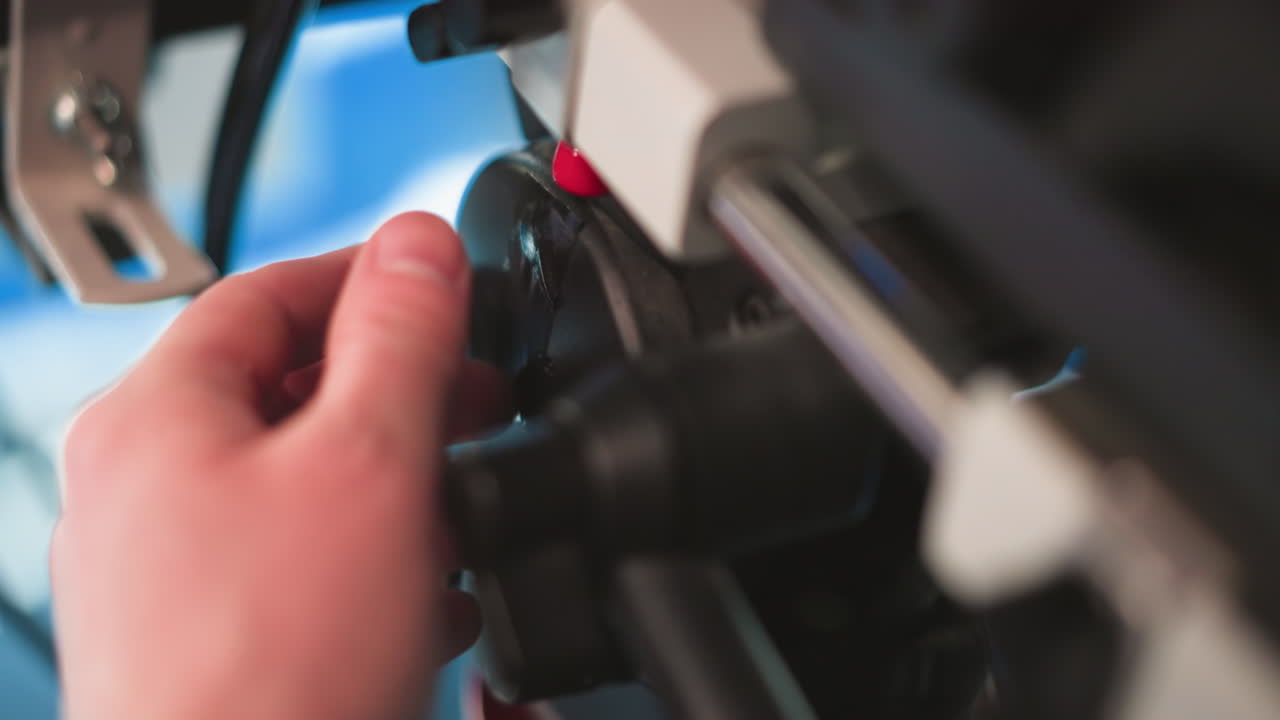 Close-up of professional camera rig showing red button and control knobs for adjusting focus or zoom. Equipment setup in broadcast studio, highlighting precise camera controls during filming