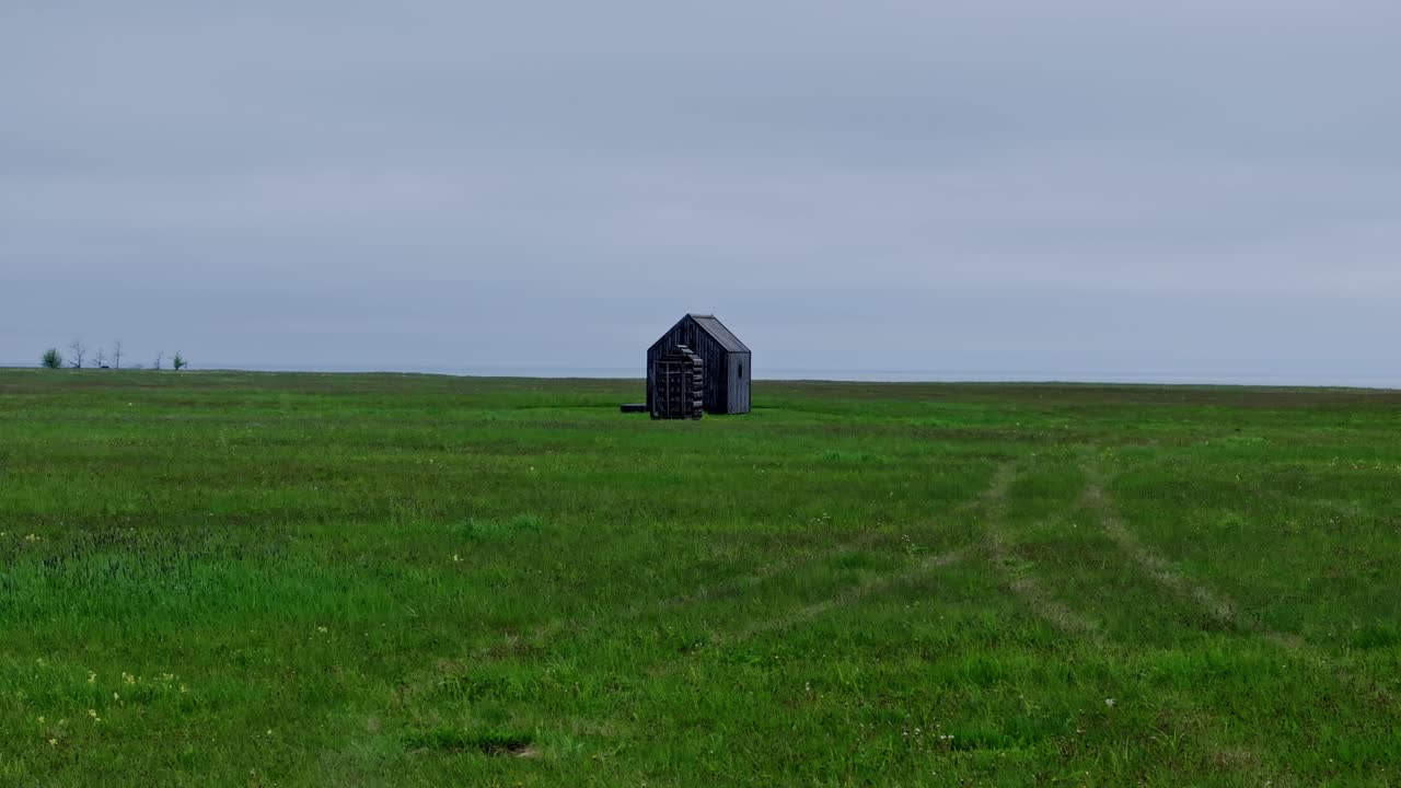 Aerial view of rural hut near coastline surrounded by vast open meadow