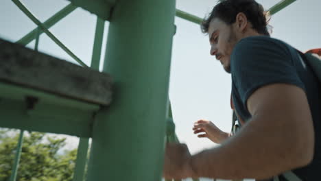 hombre caminando arriba en una escalera de caracol con una mochila naranja para llegar a la cima de una torre de vigilancia