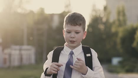 cu tracking slow motion schoolboy is walking along the street and thinking remembering