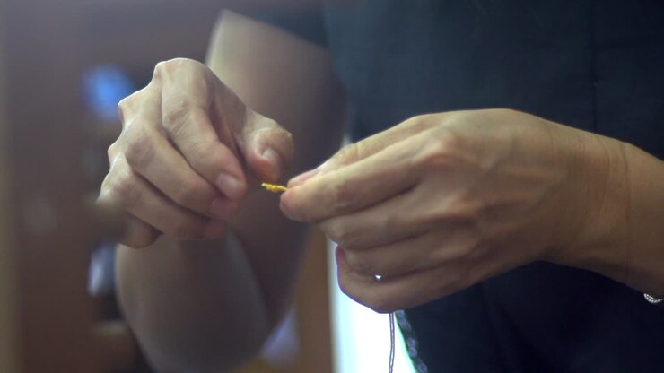 Tightening of knot on yellow yarn with fingers