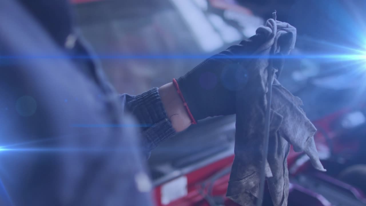 Tecnico guantato che afferra un panno e pulisce un duomo ammortizzatore rosso per la manutenzione in officina auto, mostrando lo sporco.