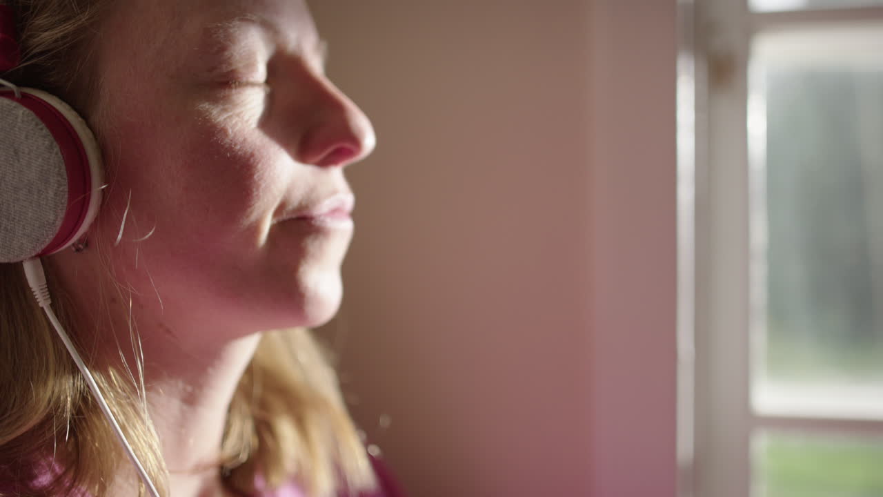 Telephoto shot on face of emotional woman listening to music with headphones