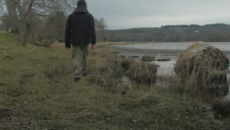 Young-man-walking-along-shoreline-in-Winter-to-free-his-mind