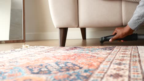 a person vacuuming under a couch