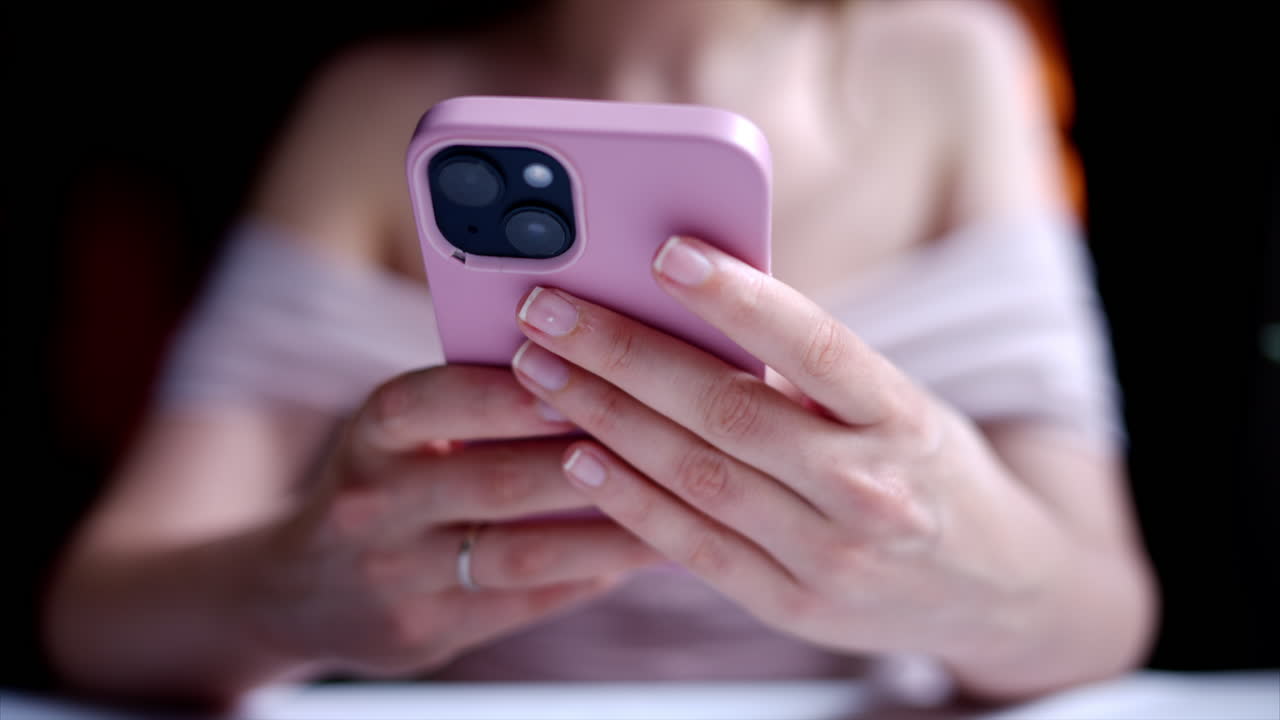 Woman working on pink mobile phone at a restaurant
