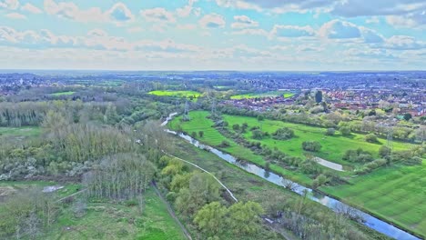 A-serene-spring-landscape-outside-of-Leicester,-UK:-a-tourist-trail-runs-along-the-calm-river-stream-while-sunray-brightens-green-lawns