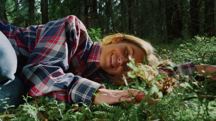 Woman lying on green grass in forest