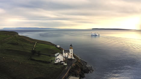 Spektakuläre-Drohnenaufnahme-Mit-Der-Fähre,-Die-Vom-Hafen-In-Den-Wunderschönen-Sonnenuntergang-Am-Leuchtturm-Vorbeifährt