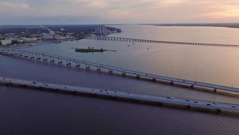 aerial wide shot showing traffic on caloosahatchee and edison bridge during sunset time - loftons island in the middle of river - fort myers, florida