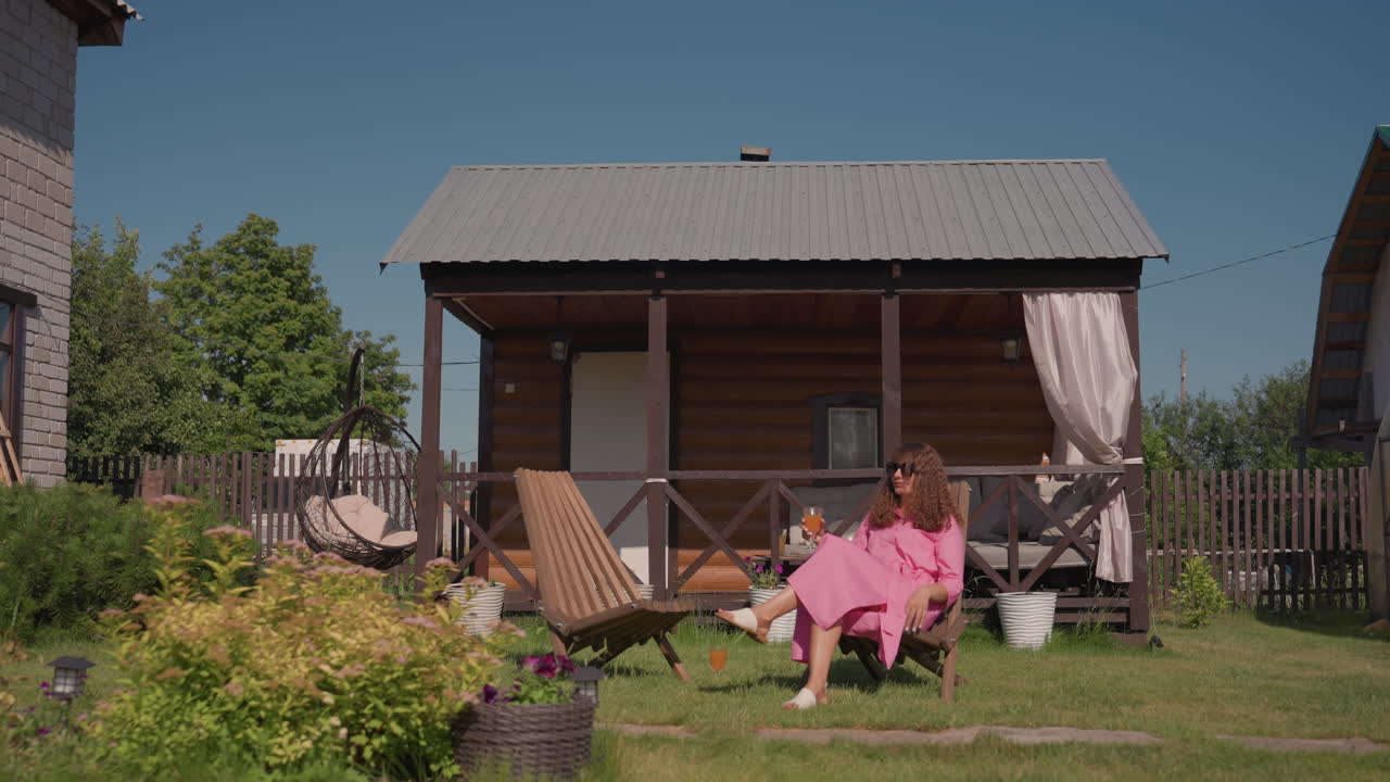Woman Arranges Outdoor Furniture, Woman Organizing Garden Chairs In Peaceful Backyard, Morning Routine Of Woman Arranging Outdoor Furniture In Serene Backyard Setting With Planters And Fencing