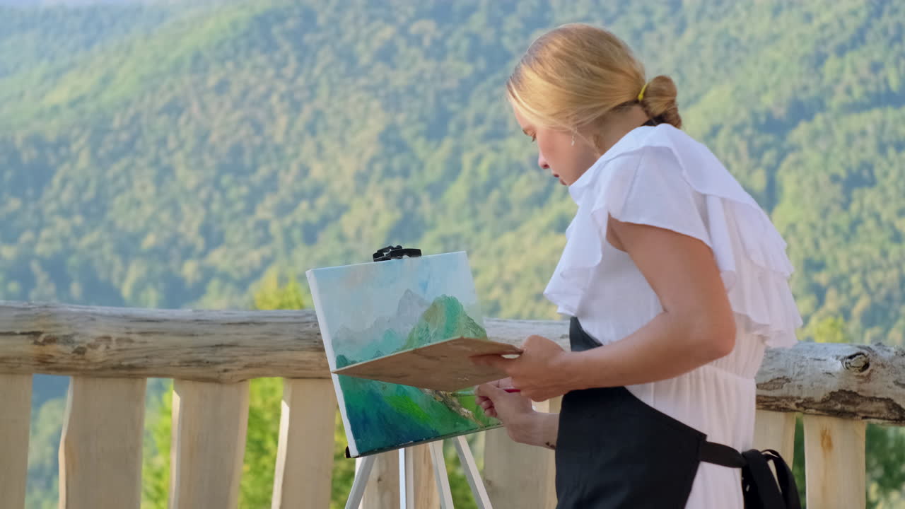 여자 가 야외 에서 산의 풍경 을 그린다
