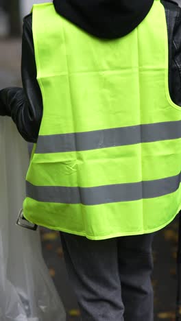 person cleaning the street with a safety vest