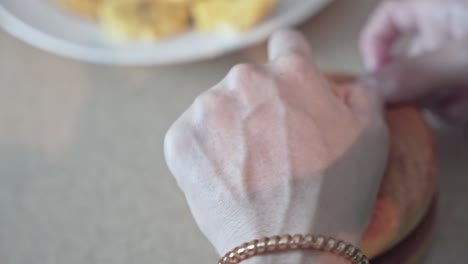 hands mashing banana pieces with wooden masher