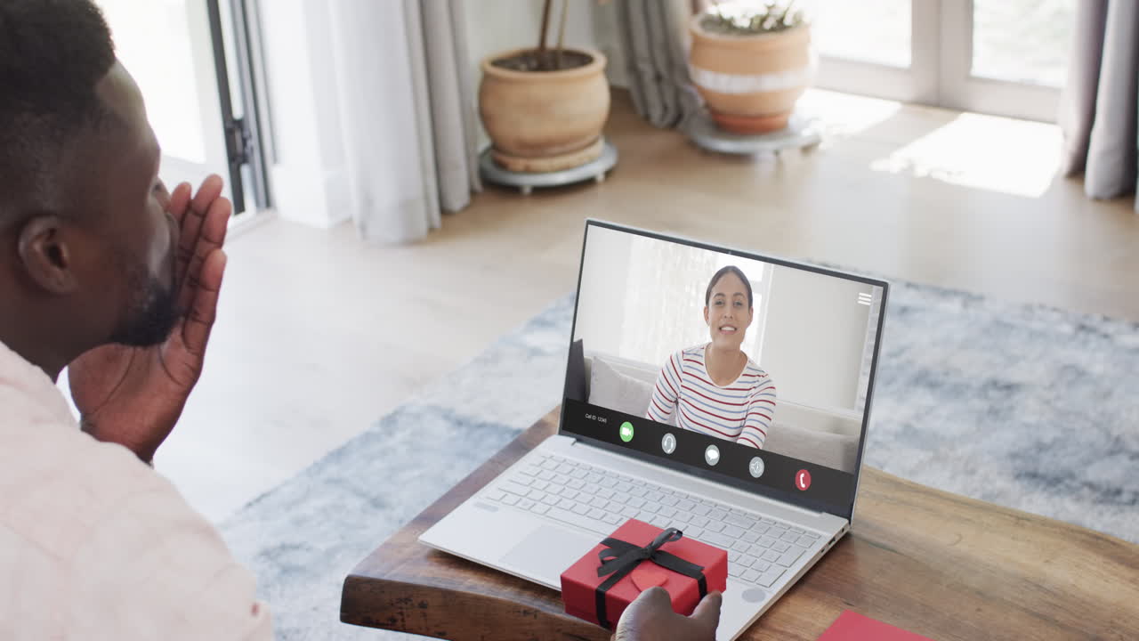 African american man holding gift and talking with biracial woman on laptop screen