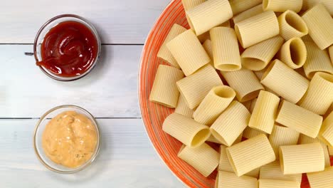 uncooked raw italian paccheri pasta rotating slowly on turntable in dish.