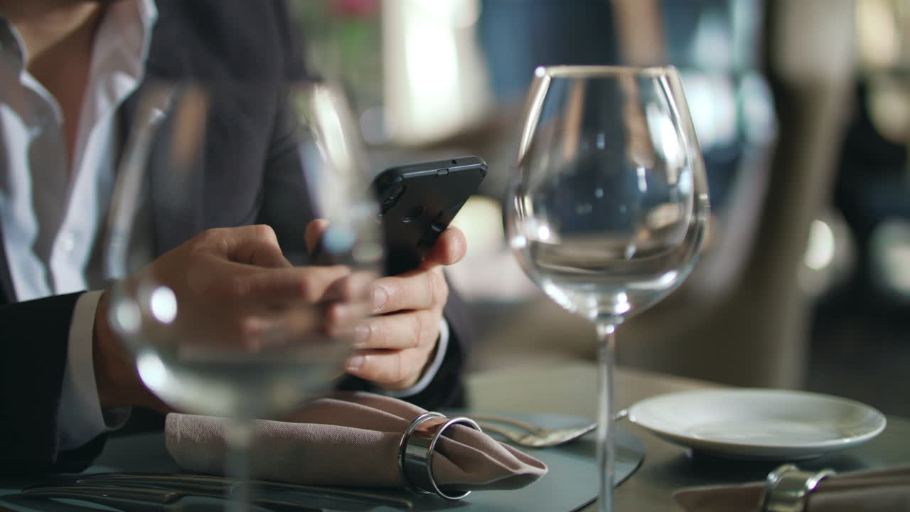 Male hands typing phone at restaurant table. Businessman using smartphone