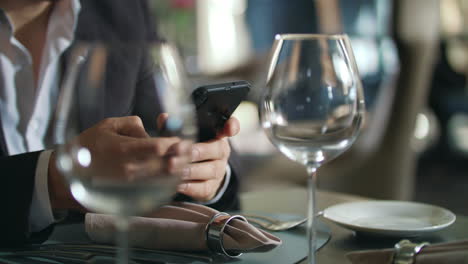 male hands typing phone at restaurant table. businessman using smartphone