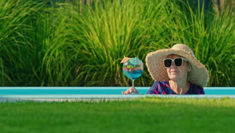 senior woman relaxing by the pool with a cocktail