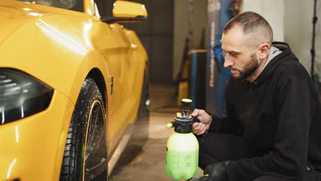 man washing a yellow sports car in a garage