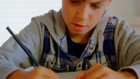 front view of caucasian boy doing his homework at dining table in a comfortable home 4k