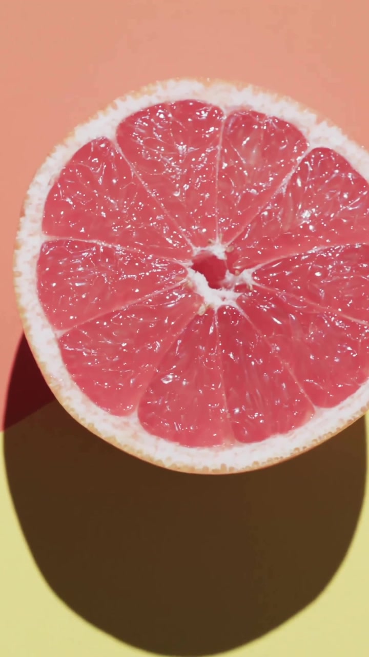 Composizione di mezzo pompelmo e foglie rosse e blu su sfondo giallo e rosso