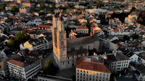 vista aérea giratoria de una iglesia de grossmünster que brilla intensamente al atardecer en zurich, suiza, rápido