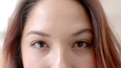 portrait close up of eyes of happy biracial woman smiling at home, copy space, slow motion