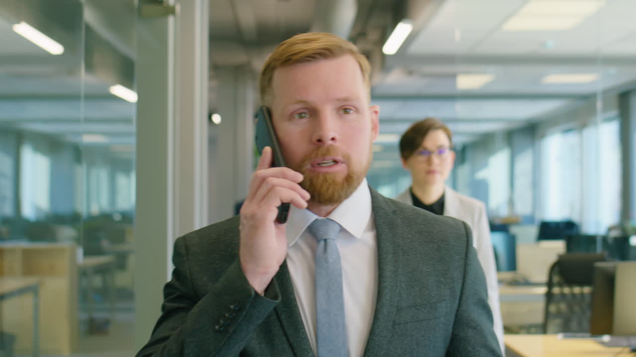 Uomo d'affari che cammina in ufficio e parla al telefono